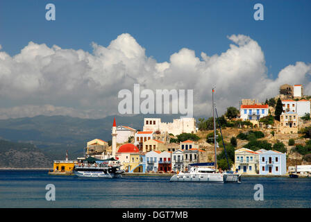 Case e barche nella baia con la costa turca sul retro, Megisti città sull isola di Kastellorizo, Meis, isole Dodecanesi, Egeo Foto Stock