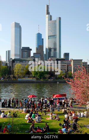 La gente sulla riva del fiume Main, Schaumain Kai, Museumsufer, nella parte anteriore della skyline di ufficio e servizi bancari Foto Stock