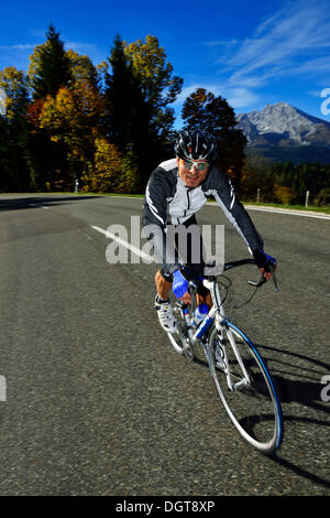 Ciclista a cavallo lungo la Obersalzbergstrasse, Monte Watzmann, Berchtesgaden, Alta Baviera, Baviera Foto Stock