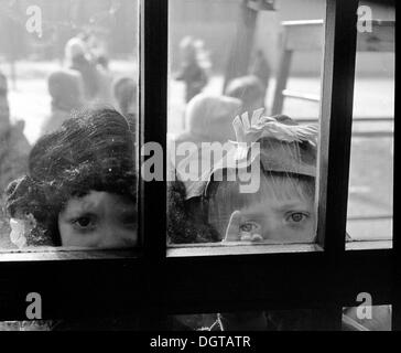 I bambini in abito di fantasia guardando attraverso una porta di vetro, Lipsia, Germania orientale, circa 1976 Foto Stock