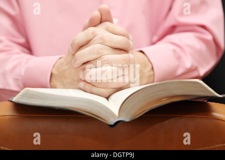 L uomo ripiegato le mani in preghiera sulla Bibbia Foto Stock