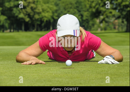 Il Golfer soffiando la pallina da golf nel foro Foto Stock