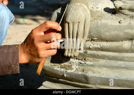 Il Buddismo Theravada, scalpellino, lavorando su un delicato dettaglio, mano di una statua del Buddha, Wat Xayaphoum tempio, Savannakhet, Laos Foto Stock