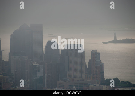 Vista dall'Empire State Building oltre i grattacieli verso la Statua della Libertà nella nebbia, nebbia Distretto finanziario Foto Stock