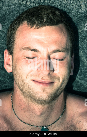 Primo piano del giovane uomo che dorme sul asciugamano sulla spiaggia. Foto Stock