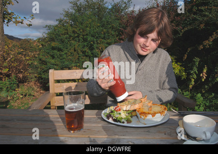 Un 18yr old adolescente di mangiare un pasto da pub. Foto Stock