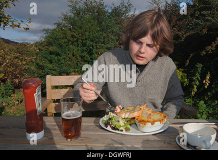 Un 18yr old adolescente di mangiare un pasto da pub. Foto Stock