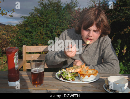 Un 18yr old adolescente di mangiare un pasto da pub. Foto Stock