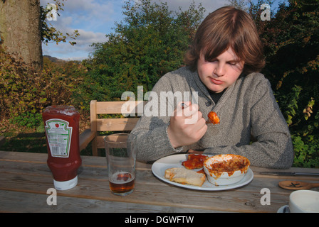 Un 18yr old adolescente di mangiare un pasto da pub. Foto Stock