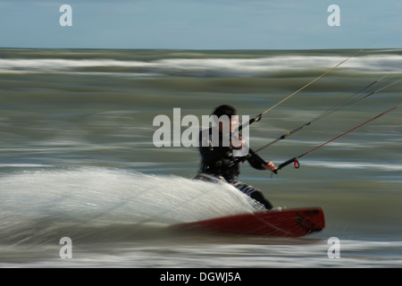 Kitesurfer cavalcando le onde panning shoot Foto Stock