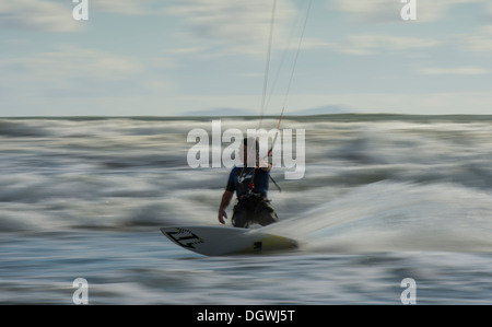 Kitesurfer cavalcando le onde panning shoot Foto Stock