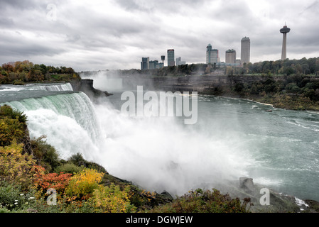 Cascate del Niagara Cascate americane e Horseshoe Cascate del Niagara New York // le Cascate americane (a sinistra) alle Cascate del Niagara sul fiume Niagara al confine tra gli Stati Uniti e il Canada. In lontananza, appena a sinistra degli edifici, si trovano le più grandi Horseshoe Falls (o Canadian Falls). Foto Stock