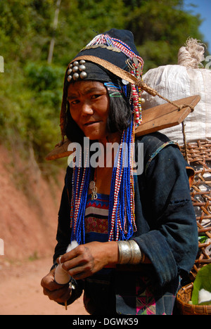 La povertà, ritratto, donna Akha Djepia gruppo etnico, tradizionali abiti colorati, cappuccio per un cappello, di filatura del cotone in Foto Stock