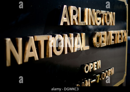 ARLINGTON, Virginia, Stati Uniti: L'impressionante insegna nera e dorata che segna l'ingresso al cimitero nazionale di Arlington si erge come una solenne porta d'ingresso al terreno più sacro d'America. Questo iconico simbolo accoglie i visitatori nel luogo di riposo finale di centinaia di migliaia di veterani militari, che fungono da commovente ricordo dei sacrifici fatti al servizio della nazione. Foto Stock