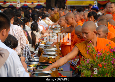 Il Buddismo Theravada, That Luang Festival, Tak Bat, monaci in piedi dietro alms bocce, credenti, pellegrini dando alms Foto Stock