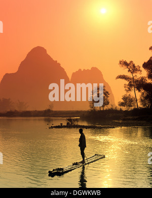 Pescatore su una zattera di bamboo sul Li Jiang fiume carsico paesaggio di montagna nei pressi di Yangshuo, Guilin, Guangxi, Cina e Asia Foto Stock