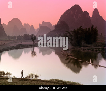 Carso paesaggio di montagna, uomo in piedi accanto al fiume Yulong, Yangshuo, Li Jiang River, Guilin, Guangxi, Cina e Asia Foto Stock