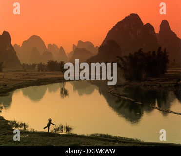 Carso paesaggio di montagna, l'uomo facendo Tai Chi accanto al fiume Yulong, Yangshuo, Li Jiang River, Guilin, Guangxi, Cina e Asia Foto Stock