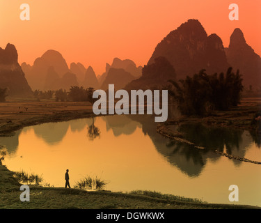 Carso paesaggio di montagna, uomo in piedi accanto al fiume Yulong, Yangshuo, Li Jiang River, Guilin, Guangxi, Cina e Asia Foto Stock