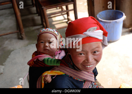 Red dao tribù Donna con bambino legato al suo ritorno in Ta Phin Village, vicino a Sapa in Vietnam Foto Stock