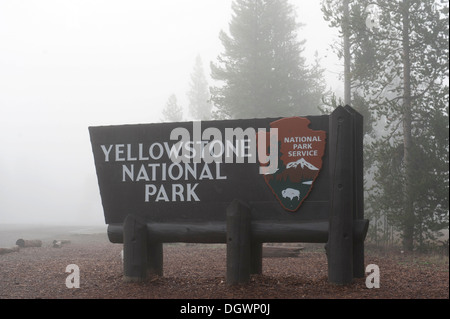 Ingresso, cartello in legno nella nebbia, National Park Service, Ingresso Ovest, il Parco Nazionale di Yellowstone, West Yellowstone, Montana Foto Stock