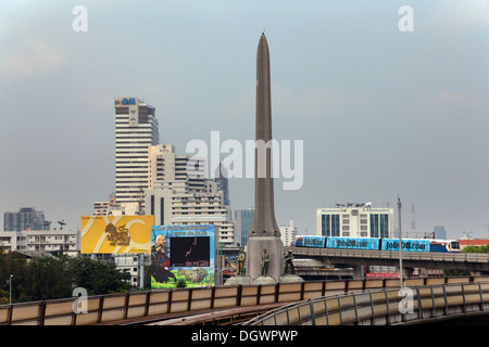 La colonna della vittoria e lo Skytrain nel quartiere Ratchathewi, Bangkok, Thailandia, Asia Foto Stock