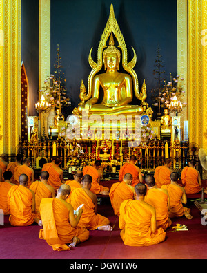 I monaci in preghiera di fronte al Phra Phutthachinnarat, statua di Buddha nel tempio in marmo di Wat Benchamabophit, Bangkok Foto Stock