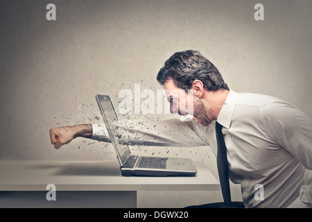 Lavoratore di ufficio getta un punzone attraverso un schermo di computer portatile Foto Stock