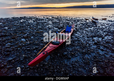 Kayak spiaggiata sulla spiaggia rocciosa in Alaska al tramonto in estate Foto Stock