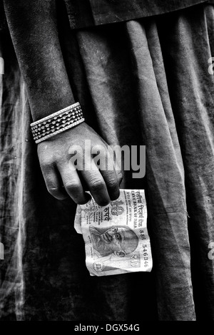 Poveri di casta inferiore indiano le ragazze di strada mano che tiene una decina di rupie nota. India. Monocromatico Foto Stock