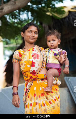 Giovani di casta inferiore Indian ragazza adolescente tenendo la sua bambina. Andhra Pradesh, India Foto Stock
