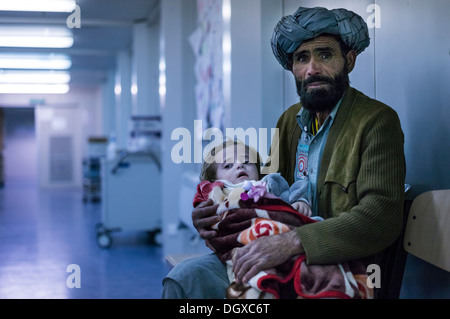 Uomo afgano con un bambino in attesa di trattamento in ospedale da campo di PRT Feyzabad azionata dall'esercito tedesco, Feyzabad, Feyzabad Foto Stock