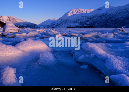 Fiordo con coperte di neve pietre e ice floes davanti a una catena montuosa, Tromsø, ‪Troms, Norvegia settentrionale, Norvegia Foto Stock