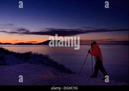 Fotografo di fronte a un fiordo al tramonto, Sommeroya, Tromsø, ‪Troms, Norvegia settentrionale, Norvegia Foto Stock