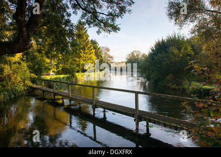 Il Footbridge sopra l'acqua come la mattina presto il sole riflette sul fiume Test in Hampshire. Foto Stock
