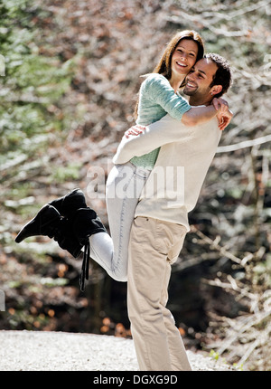 Giovane uomo il prelievo di una giovane donna, entrambi sorridenti, Austria Foto Stock