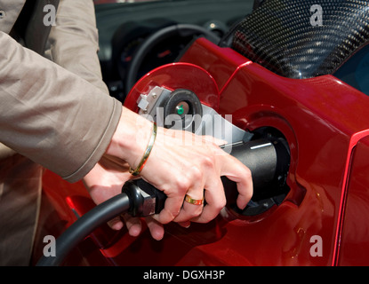 Una donna "alimentando l' una Tesla Roadster batteria veicolo elettrico in corrispondenza di una stazione di carica, Starnberg, Bavaria Foto Stock