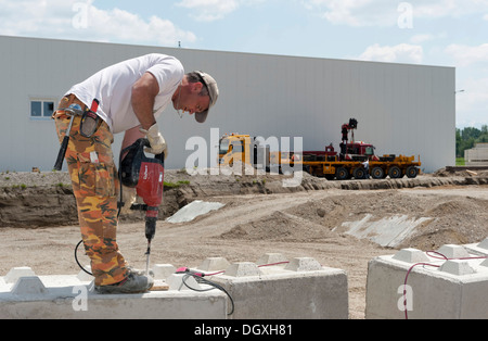 Operaio edile Fori di perforazione in blocchi di pietra che devono essere utilizzati in un sito di costruzione dei test di carico in corrispondenza di un sito in costruzione in Foto Stock
