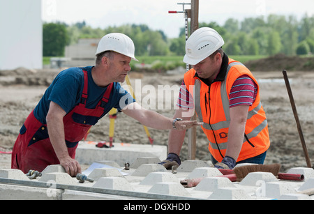 Gli ingegneri strutturali ponendo i primi blocchi durante un edificio sito test di carico in un cantiere in Fridolfing, Bavaria Foto Stock