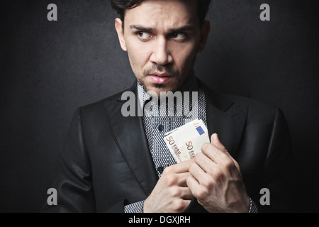 Uomo elegante nasconde una cinquantina di banconote in euro nella sua tuta camicia Foto Stock