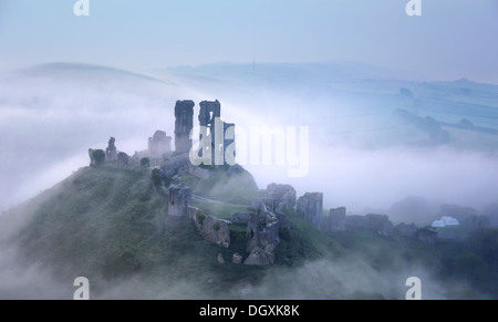 Corfe Castle Rising attraverso la mattina presto nebbie Foto Stock