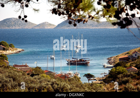 Barche a vela, compreso un tradizionale caicco, ormeggiare in Croazia Smokvika bay con più delle isole di Kornati oltre Foto Stock