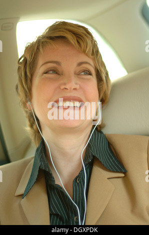 Business donna indossa le cuffie in un auto Foto Stock