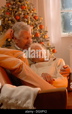 Coppia matura in amore giacente su un divano davanti a un albero di Natale Foto Stock