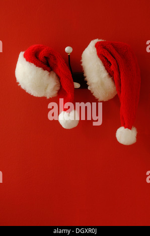 Due cappelli di Babbo Natale sul appeso sul nostalgico appendiabiti Foto Stock