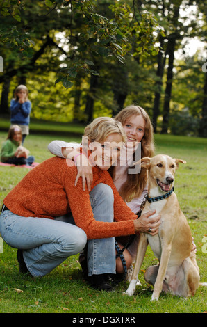 Madre e tre figlie con un cane in un parco Foto Stock