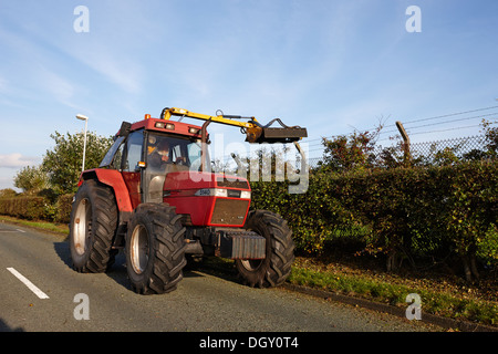 Agricoltore il taglio di siepi di strada con un trattore e attrezzatura Foto Stock