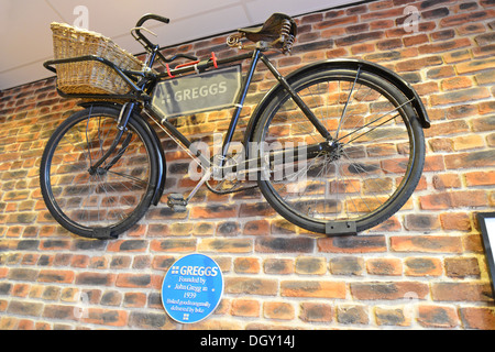 Vecchia bicicletta di consegna sulla parete del forno Greggs, High Street, Haverhill, Suffolk, Inghilterra, Regno Unito Foto Stock