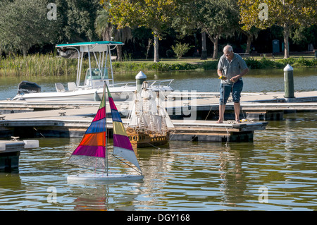 L'uomo sul dock lancia di modelli in scala di sloop con multi-strisce colorate vele e galeone spagnolo nave a vela barca sul Lago Dora. Foto Stock