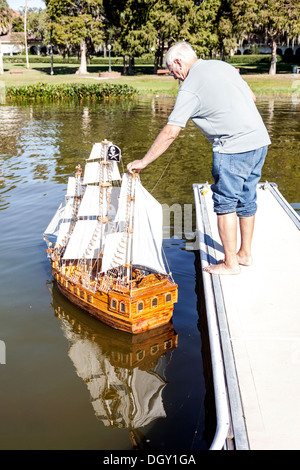 Uomo anziano pensionato titolare di pensione o di rendita si prepara a lanciare un modello in scala galeone spagnolo nave a vela sul lago di Dora in Florida. Foto Stock